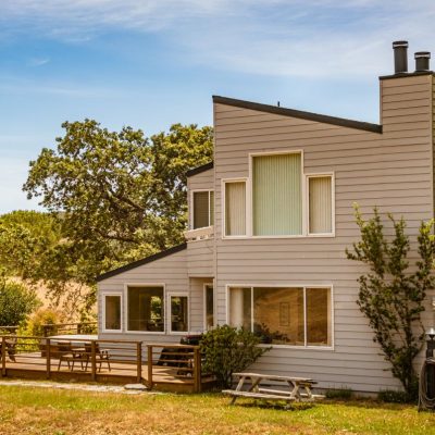 Home Contemporary suburban house featuring large glass windows and a spacious deck in a lush outdoor setting.