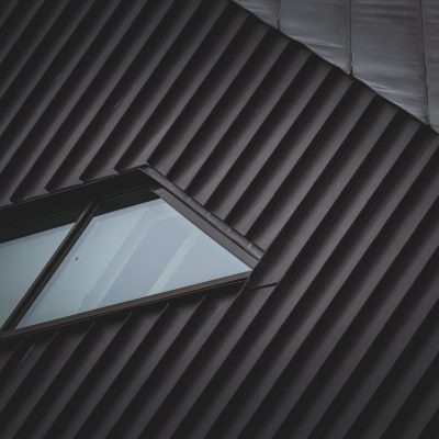 A sleek metal rooftop with a unique window, showcasing modern architectural style and geometric patterns.