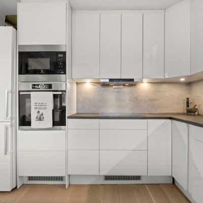 Home Sleek modern kitchen featuring white cabinetry, built-in appliances, and minimalist design.