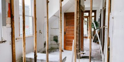 Interior view of a home under renovation with exposed wooden beams and door.
