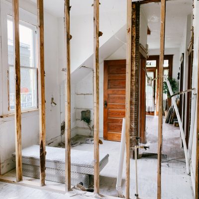 Interior view of a home under renovation with exposed wooden beams and door.