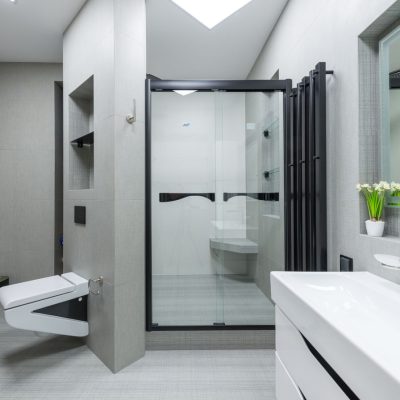 Home Sink with tap placed at wall with mirror in light spacious bathroom with toilet and glass shower cabin in apartment