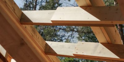 Close-up view of wooden beams forming a house roof structure against a sky background.